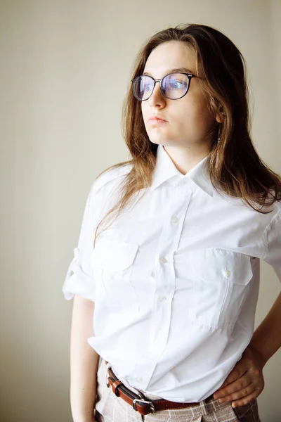 Göğüs cepleri ve kısa kolları olan beyaz gömlekli bir kız başka tarafa bakıyor. Güzel kızların saçı dökülüyor..