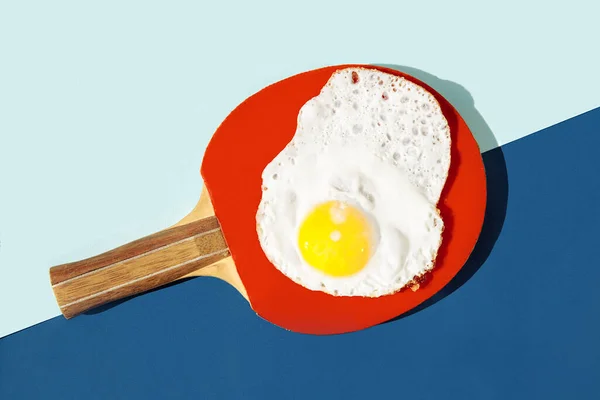 Düzensiz şekilli omlet kırmızı ping pong raketinin üzerinde yatıyor.. — Stok fotoğraf