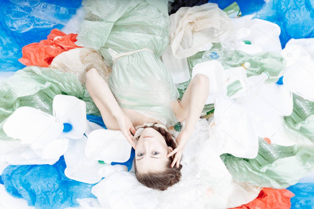 A beautiful girl of European appearance is lying on a mountain of plastic. 