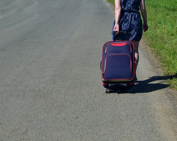 Μια Νεαρή Γυναίκα Περπατάει Ασφαλτοστρωμένο Δρόμο Μια Μπλε Ταξιδιωτική Τσάντα — Φωτογραφία Αρχείου