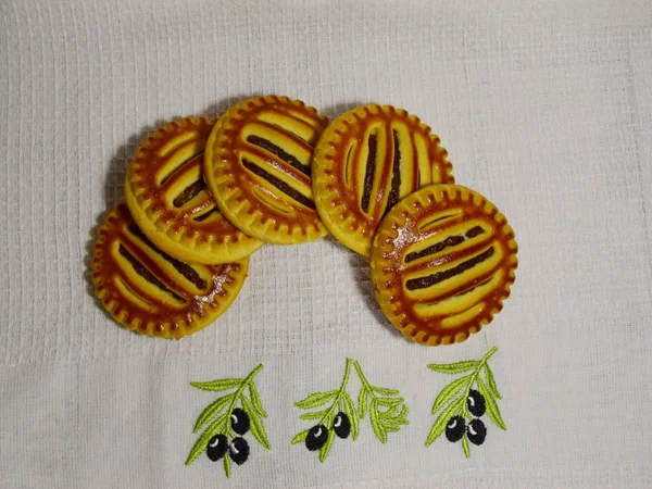 cookies with jam on a white towel lying in a semicircle in the background light concrete that lie on a wooden table, close-up. Selective focus