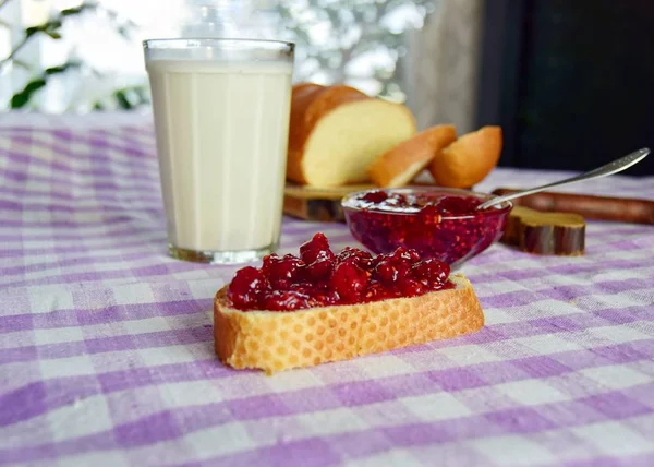 Dacha Sütü 'nde somun ekmek ve ahududu reçeli ile kahvaltı. Sovyet tarzında yakın plan bir masa örtüsü. Arka planda, kesme tahtasının üzerinde bıçakla dilimlenmiş bir somun ekmek..