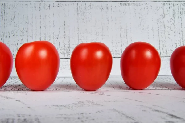 Tahta bir arka planda arka planda beş domates. Vejetaryen sağlıklı yiyecekler.