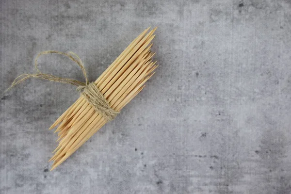 Ahşap kürdanlar, beton gri arka planda bir ağacın altında bir iple bağlanmış. Kapat..