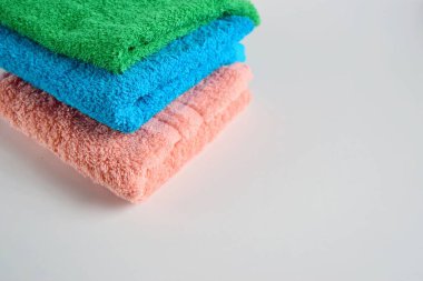 Açık arkaplanda bir yığın renkli otel havlusu.