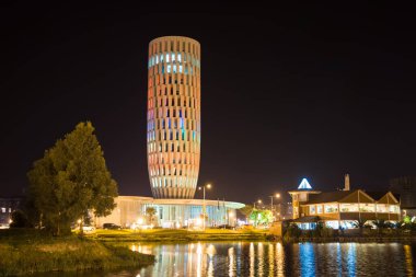 Adalet Evi, Batumi geceleri. Tatil köyünde güzel aydınlatılmış bina ve su yansıması. Gürcistan 'da modern mimari.