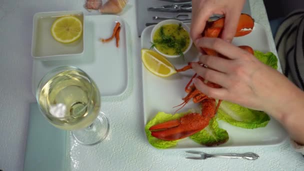 Женщина отрывается и ест лапу омара со столовыми приборами, вид сверху, 4К — стоковое видео
