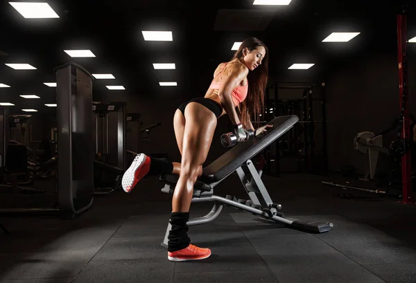 Fitness chica sexy joven en el gimnasio haciendo ejercicios con mancuerna —  Fotos de Stock