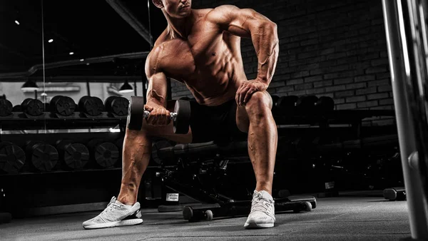 Bonito homem musculoso com corpo nu usa seu halteres para exercer — Fotografia de Stock