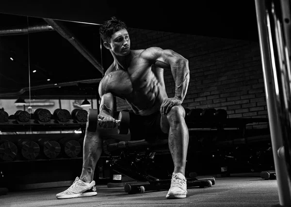 Красивый мускулистый мужчина с обнажённым телом использует гантели для тренировок. — стоковое фото