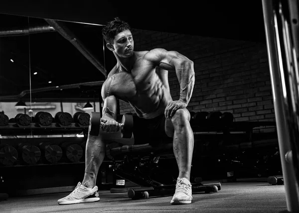 Красивый мускулистый мужчина с обнажённым телом использует гантели для тренировок. — стоковое фото