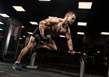 Yakışıklı ve kaslı bir adam, spor salonunda kameraya poz veriyor.