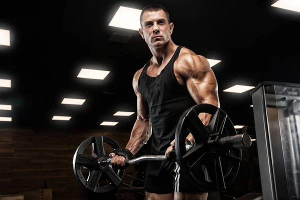 Bello uomo con grandi muscoli, in posa presso la fotocamera in palestra — Foto Stock