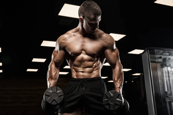 Bello uomo con grandi muscoli, in posa presso la fotocamera in palestra — Foto Stock