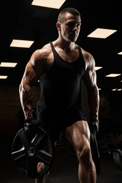 Bel homme avec de gros muscles, posant à la caméra dans la salle de gym — Photo