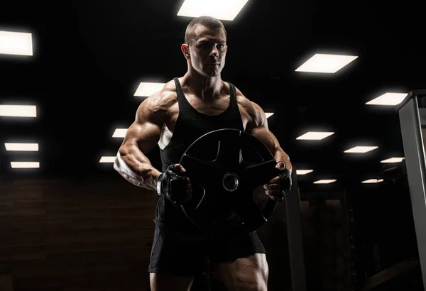 Bel homme avec de gros muscles, posant à la caméra dans la salle de gym — Photo