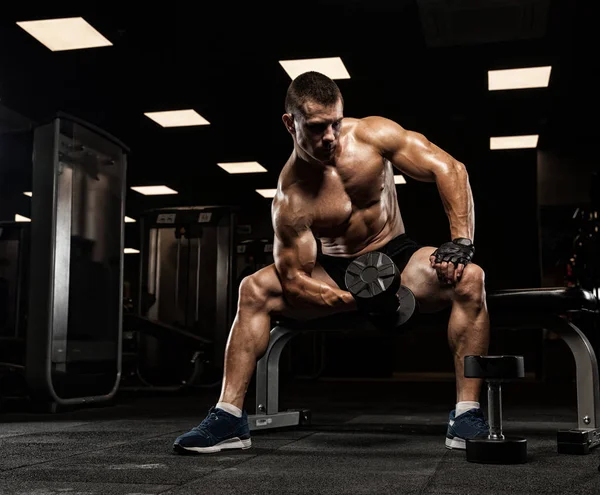 Yakışıklı ve kaslı bir adam, spor salonunda kameraya poz veriyor. — Stok fotoğraf