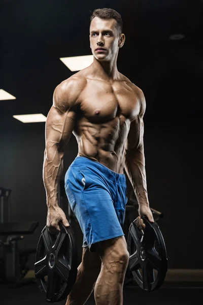 Bello uomo con grandi muscoli, in posa presso la fotocamera in palestra — Foto Stock