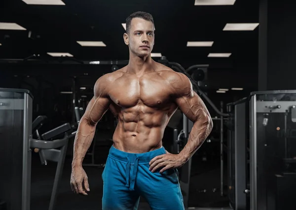 Hombre guapo con grandes músculos, posando en la cámara en el gimnasio — Foto de Stock