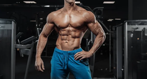 Hombre guapo con grandes músculos, posando en la cámara en el gimnasio — Foto de Stock