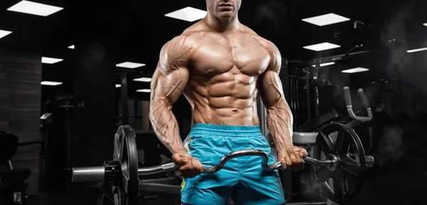 Красивый мужчина с большими мускулами, позирует перед камерой в спортзале — стоковое фото