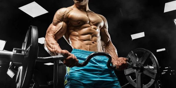 Pohledný muž s velkými svaly, pózující na kameru v tělocvičně — Stock fotografie
