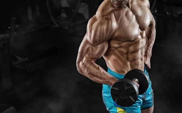 Bello uomo con grandi muscoli, in posa presso la fotocamera in palestra — Foto Stock