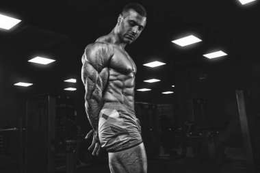 Yakışıklı ve kaslı bir adam, spor salonunda kameraya poz veriyor.