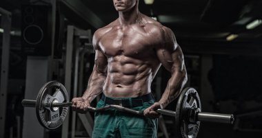 güçlü ve yakışıklı bir genç adam dumbbells ile egzersiz yaparak