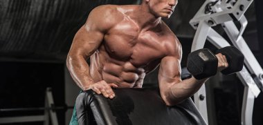 güçlü ve yakışıklı bir genç adam dumbbells ile egzersiz yaparak