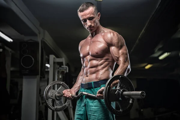 Bonito homem com grandes músculos, posando para a câmera no ginásio — Fotografia de Stock