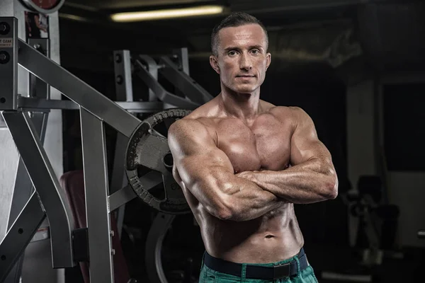 Hombre guapo con grandes músculos, posando en la cámara en el gimnasio — Foto de Stock