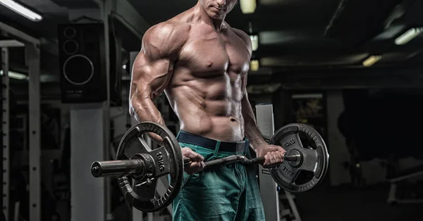 Hombre guapo con grandes músculos, posando en la cámara en el gimnasio — Foto de Stock