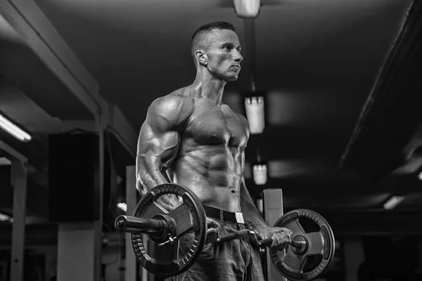 Bel homme avec de gros muscles, posant à la caméra dans la salle de gym — Photo