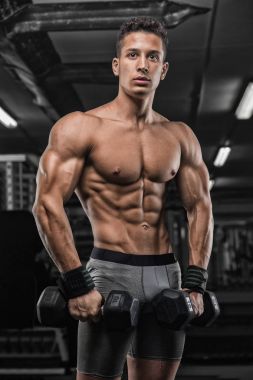 güçlü ve yakışıklı bir genç adam dumbbells ile egzersiz yaparak