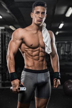 güçlü ve yakışıklı bir genç adam dumbbells ile egzersiz yaparak