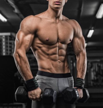 güçlü ve yakışıklı bir genç adam dumbbells ile egzersiz yaparak