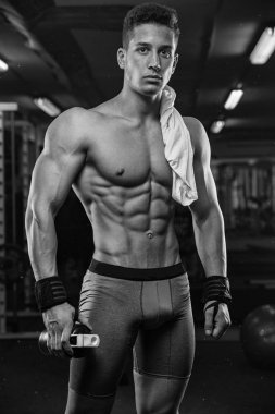 güçlü ve yakışıklı bir genç adam dumbbells ile egzersiz yaparak