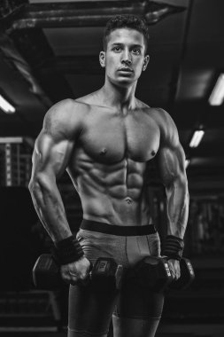 güçlü ve yakışıklı bir genç adam dumbbells ile egzersiz yaparak