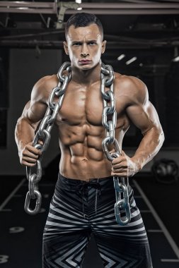 Yakışıklı ve kaslı bir adam, spor salonunda kameraya poz veriyor.