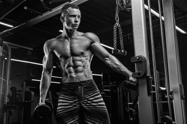 Spor salonunda ağırlık kaldıran genç bir vücut geliştirici..