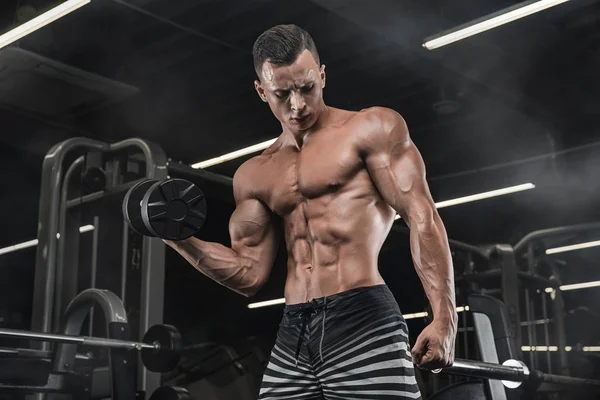 Bodybuilder trainiert mit Hanteln im Fitnessstudio — Stockfoto