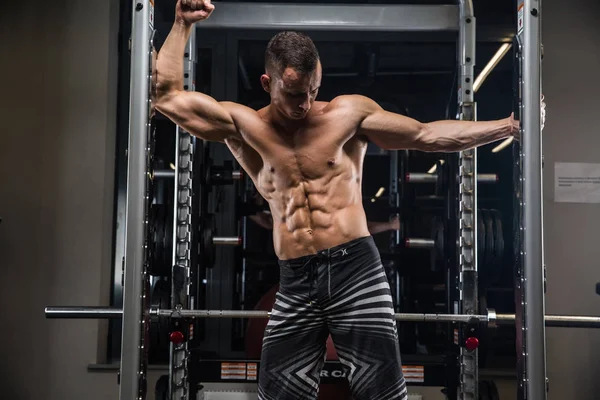 Culturista adulto joven haciendo levantamiento de pesas en el gimnasio. — Foto de Stock