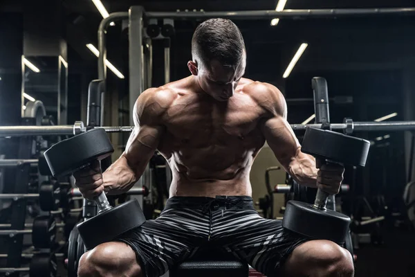 Culturista adulto joven haciendo levantamiento de pesas en el gimnasio. — Foto de Stock