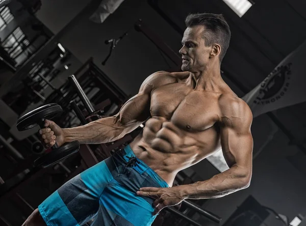 Bonito homem com grandes músculos, posando para a câmera no ginásio — Fotografia de Stock