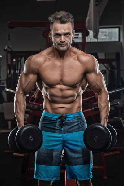 Bello uomo con grandi muscoli, in posa presso la fotocamera in palestra — Foto Stock