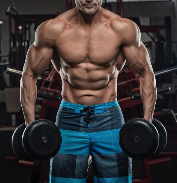 Bello uomo con grandi muscoli, in posa presso la fotocamera in palestra — Foto Stock