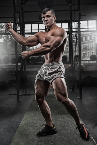 Modelo de fitness Hombre posando en el gimnasio. Hombre guapo con grandes  músculos, posando en la cámara en el gimnasio Fotografía de stock - Alamy