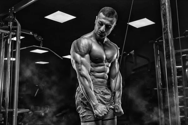 М'язистий чоловік, що працює в тренажерному залі, виконує вправи на трицепсах, інсульт — стокове фото