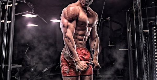 Hombre en el gimnasio. Musculoso culturista chico haciendo ejercicios con barbo — Foto de Stock